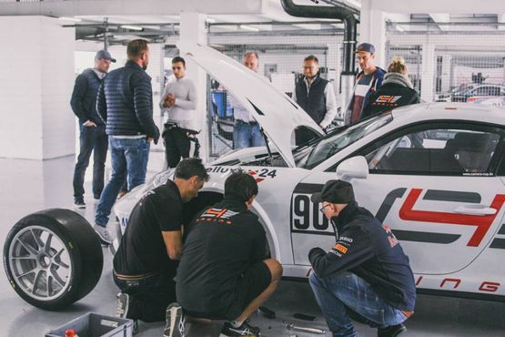 mehrere Personen rund um einen Rennwagen, Reifenwechsel