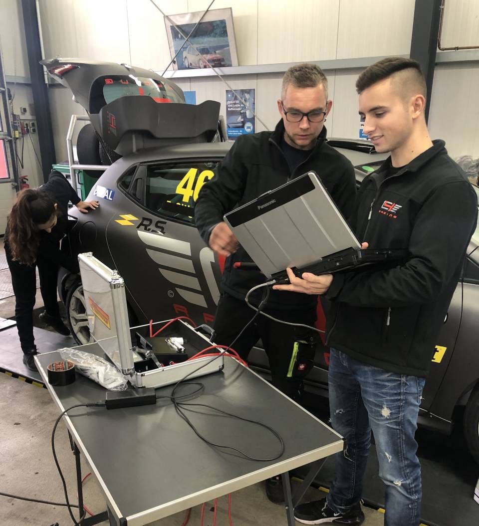 zwei Männer mit Laptop vor einem Rennwagen