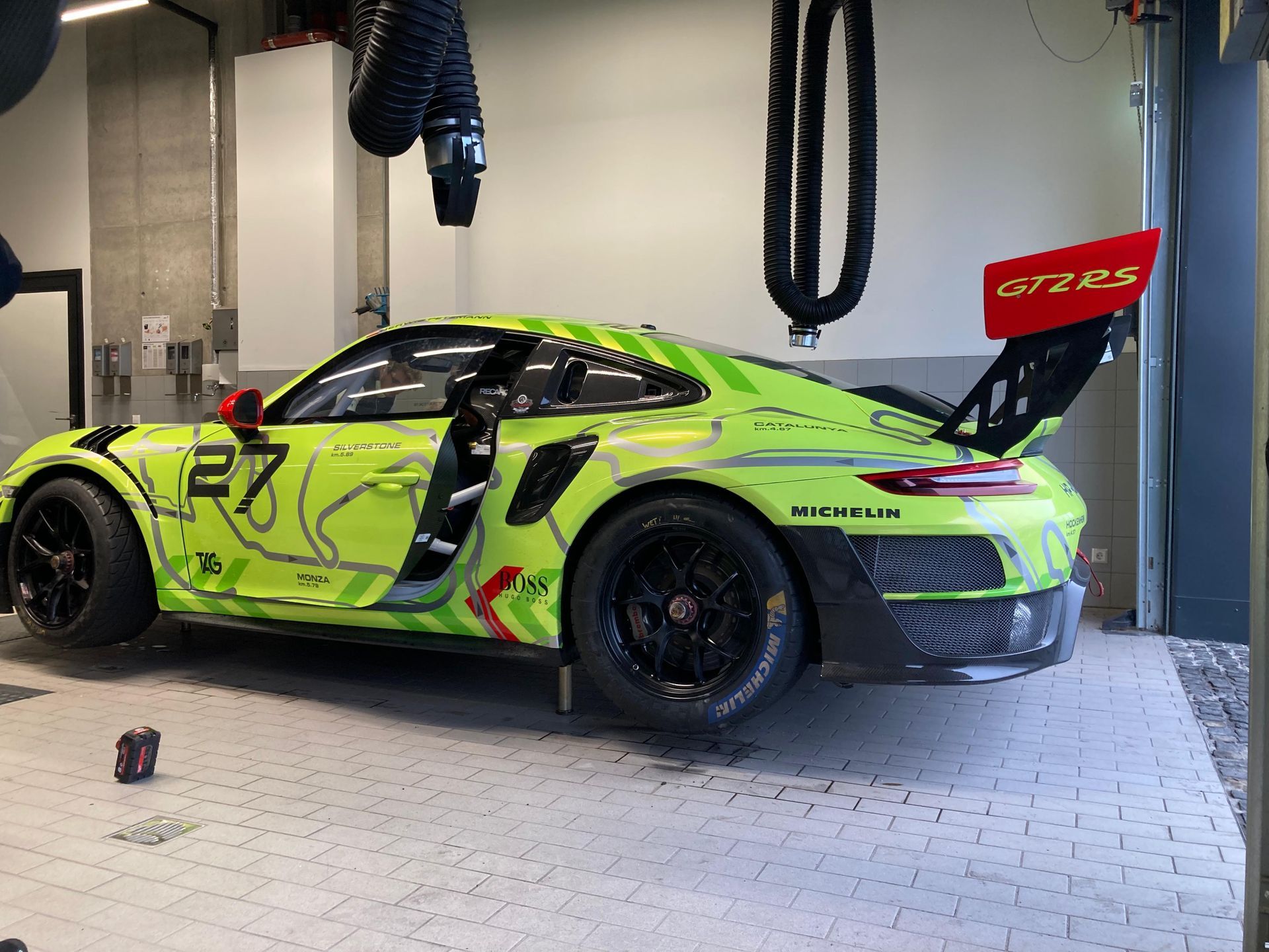 Grüner und schwarzer Rennwagen, Nummer 27, in einer Garage geparkt.