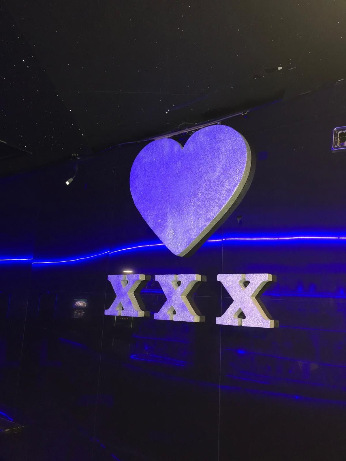 Un corazón morado está sentado encima de un cartel que dice xxx.