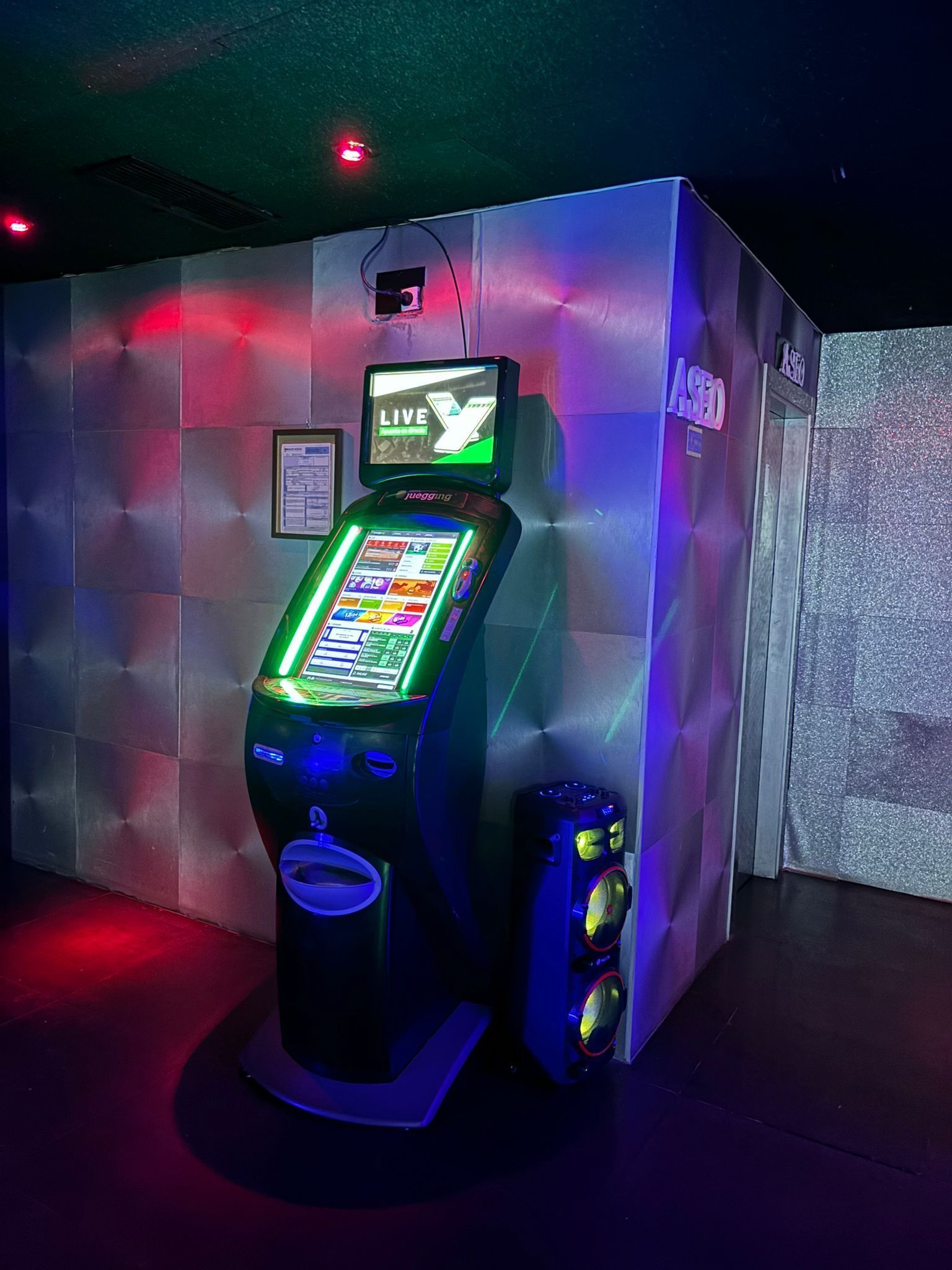 Una máquina de videojuegos está junto a una pared en una habitación oscura.