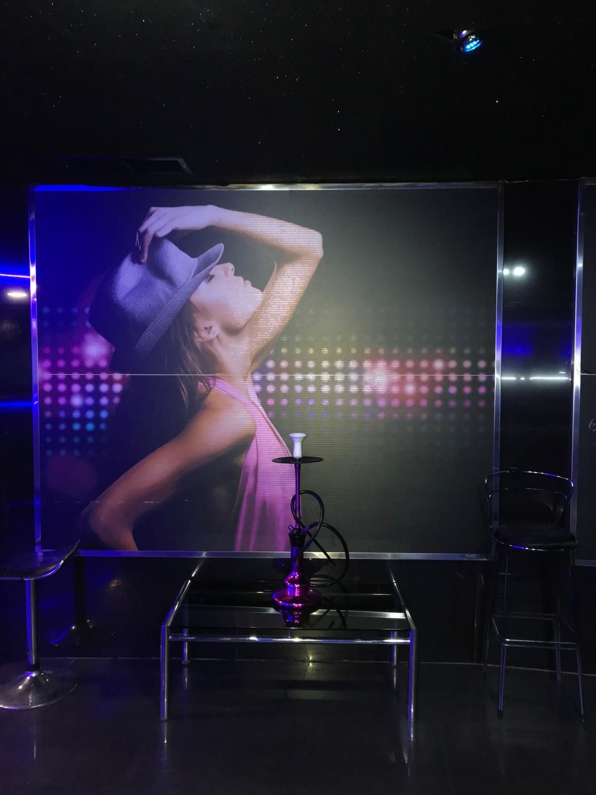 Una mujer con un vestido rosa está bailando delante de una pipa de agua.