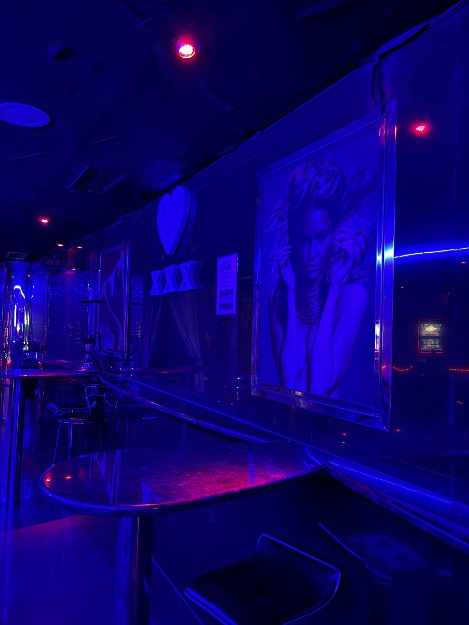 Una habitación oscura con luces azules y una imagen de una mujer en la pared.