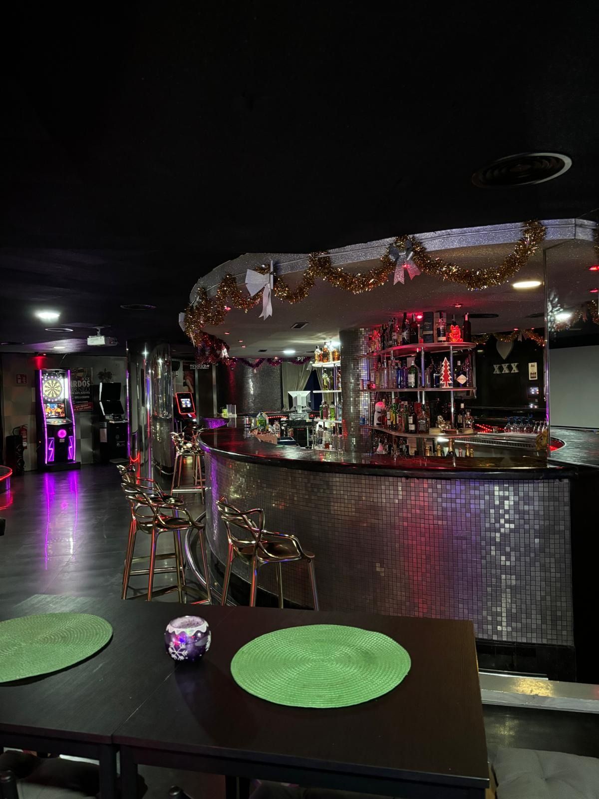 Una habitación oscura con mesas y sillas frente a un bar.