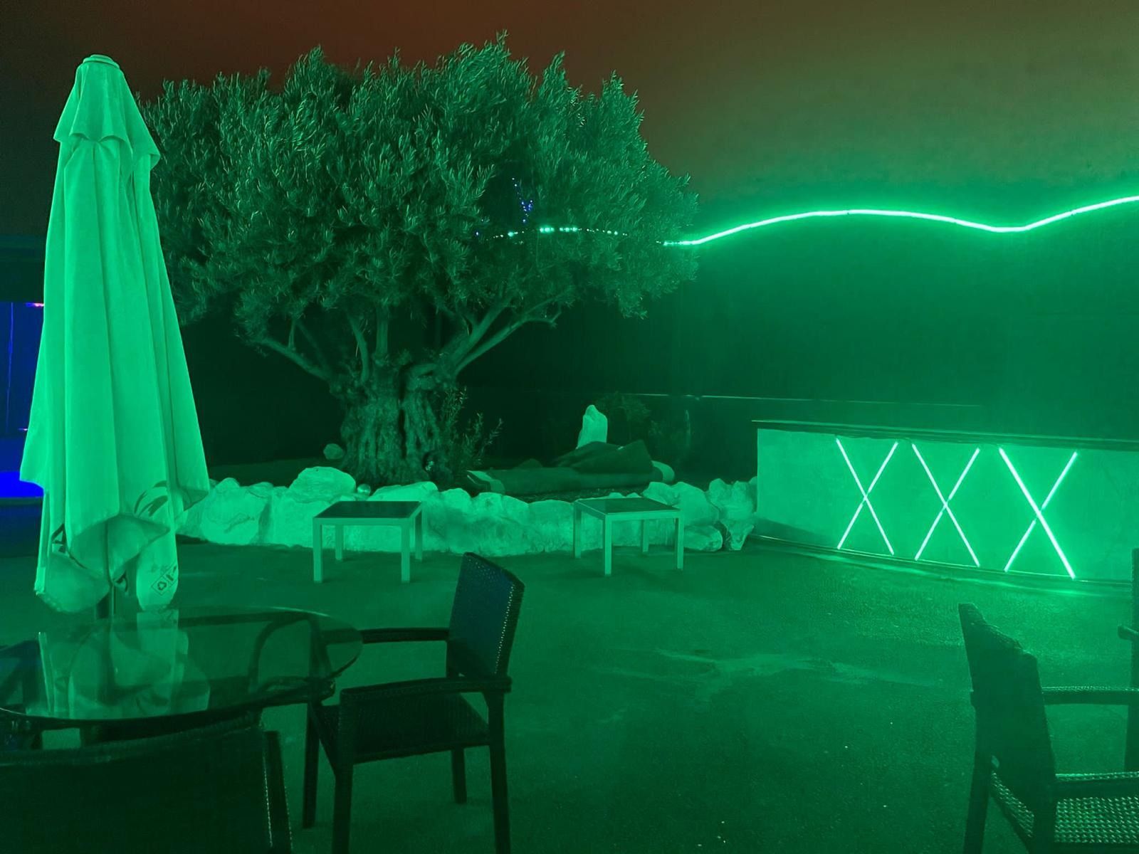 Una luz verde brilla en un patio con una mesa y sillas.