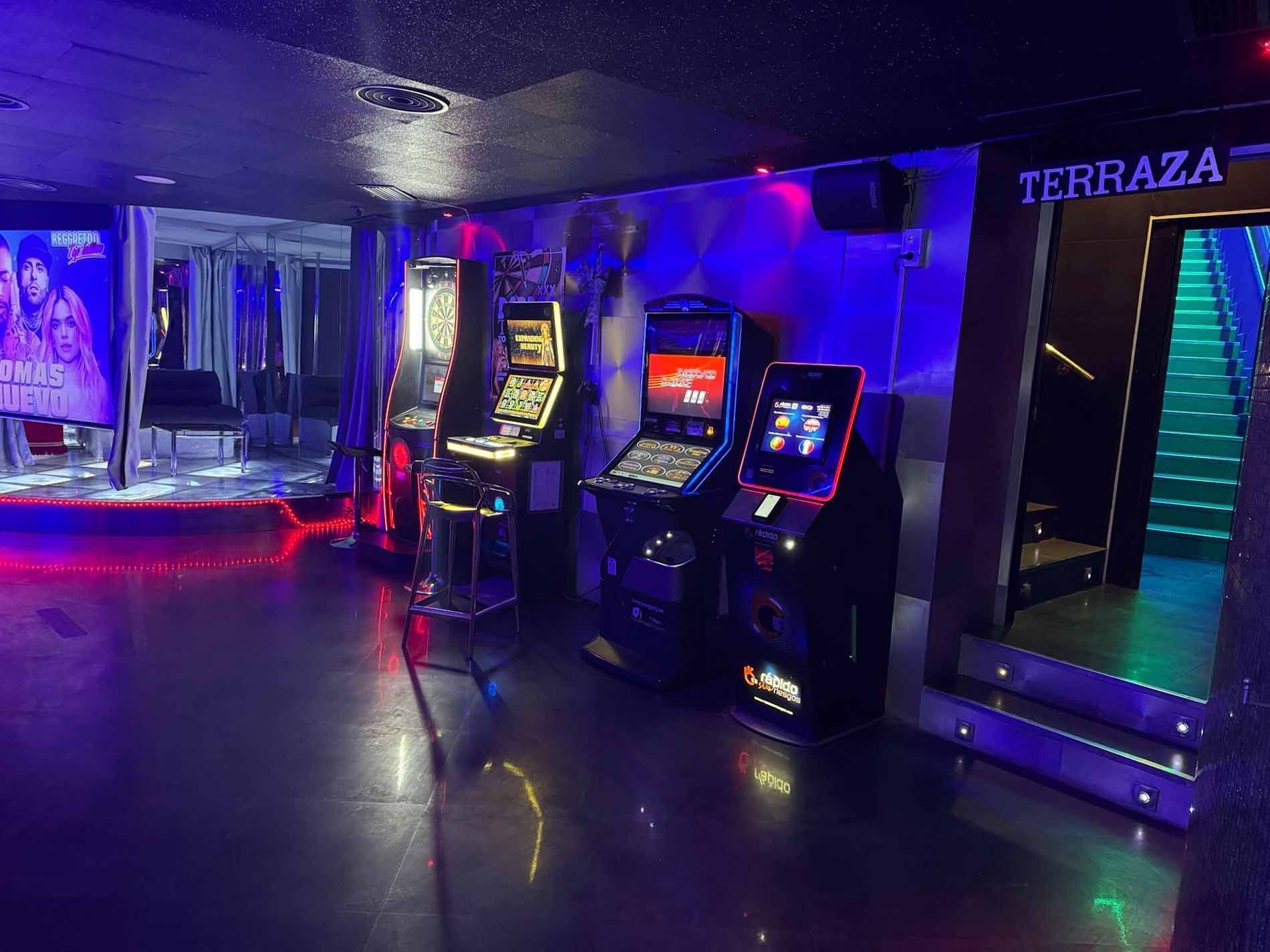 Una fila de juegos de arcade están alineados en una habitación oscura.