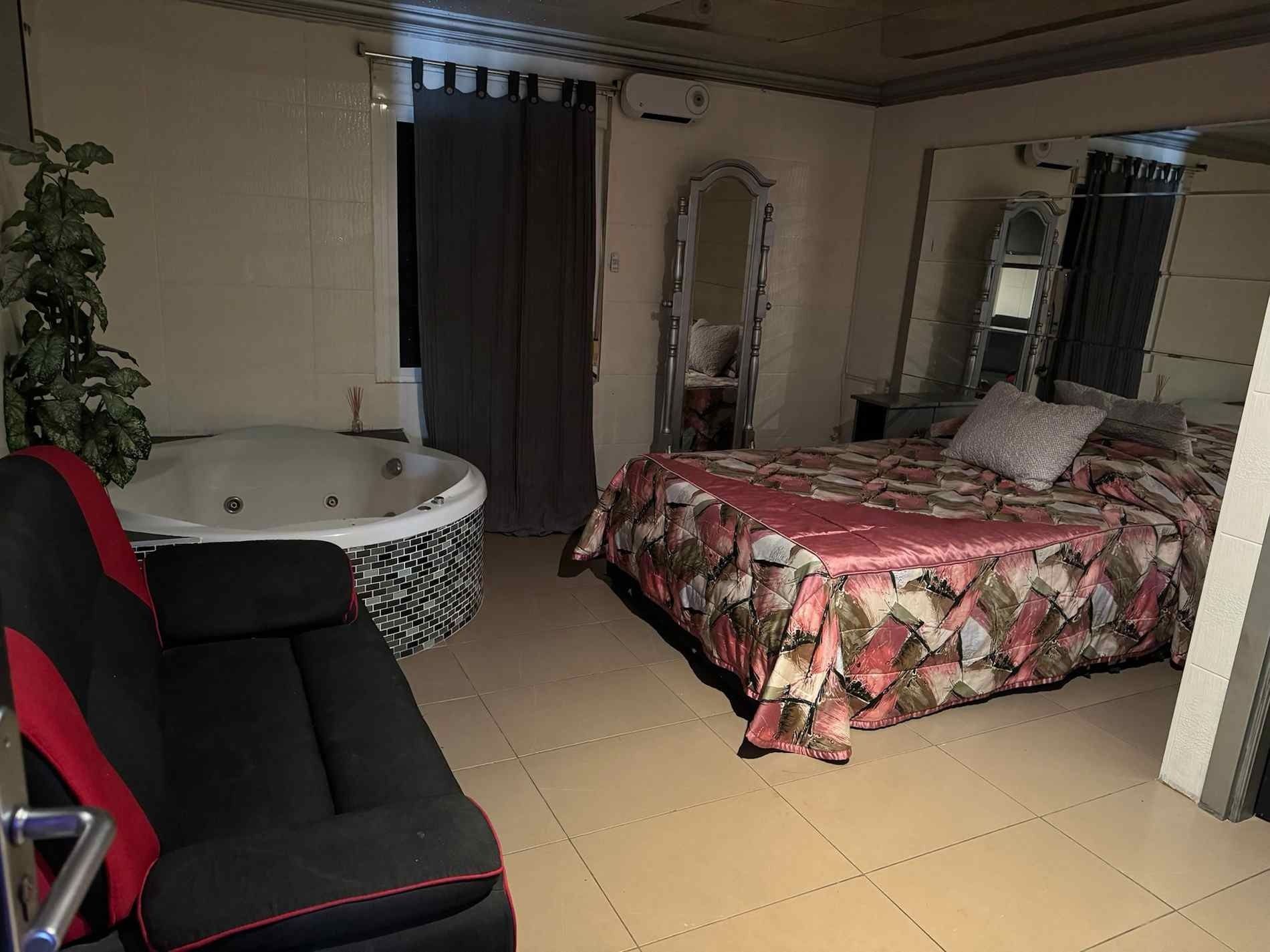 Una habitación de hotel con cama, sofá y jacuzzi.