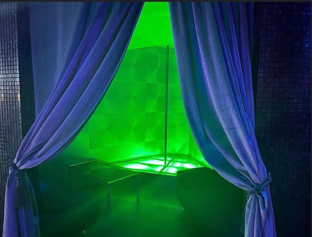 Una habitación con una luz verde brillando a través de las cortinas.