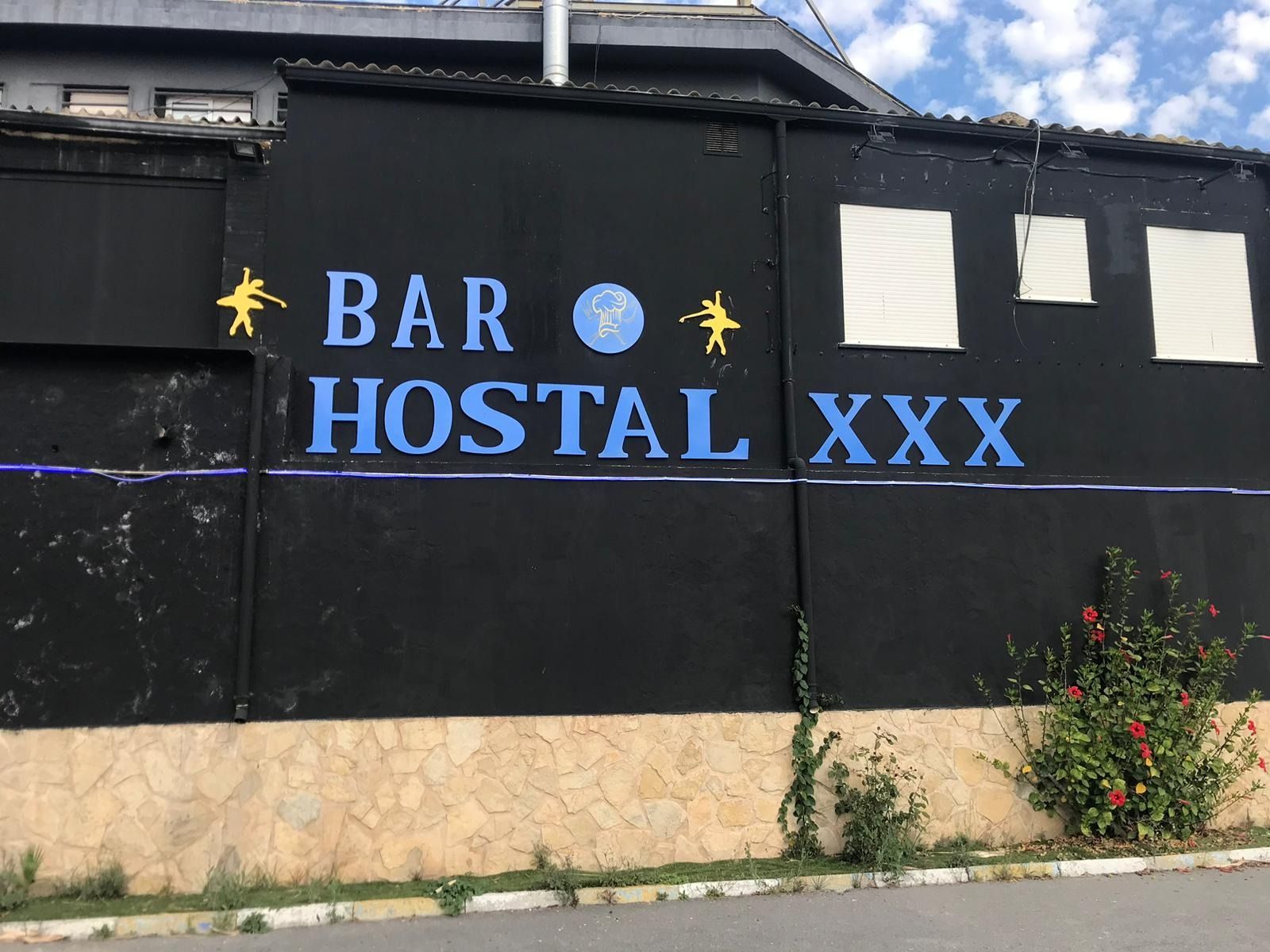 Una pared negra con escritura azul que dice bar hostal xxx