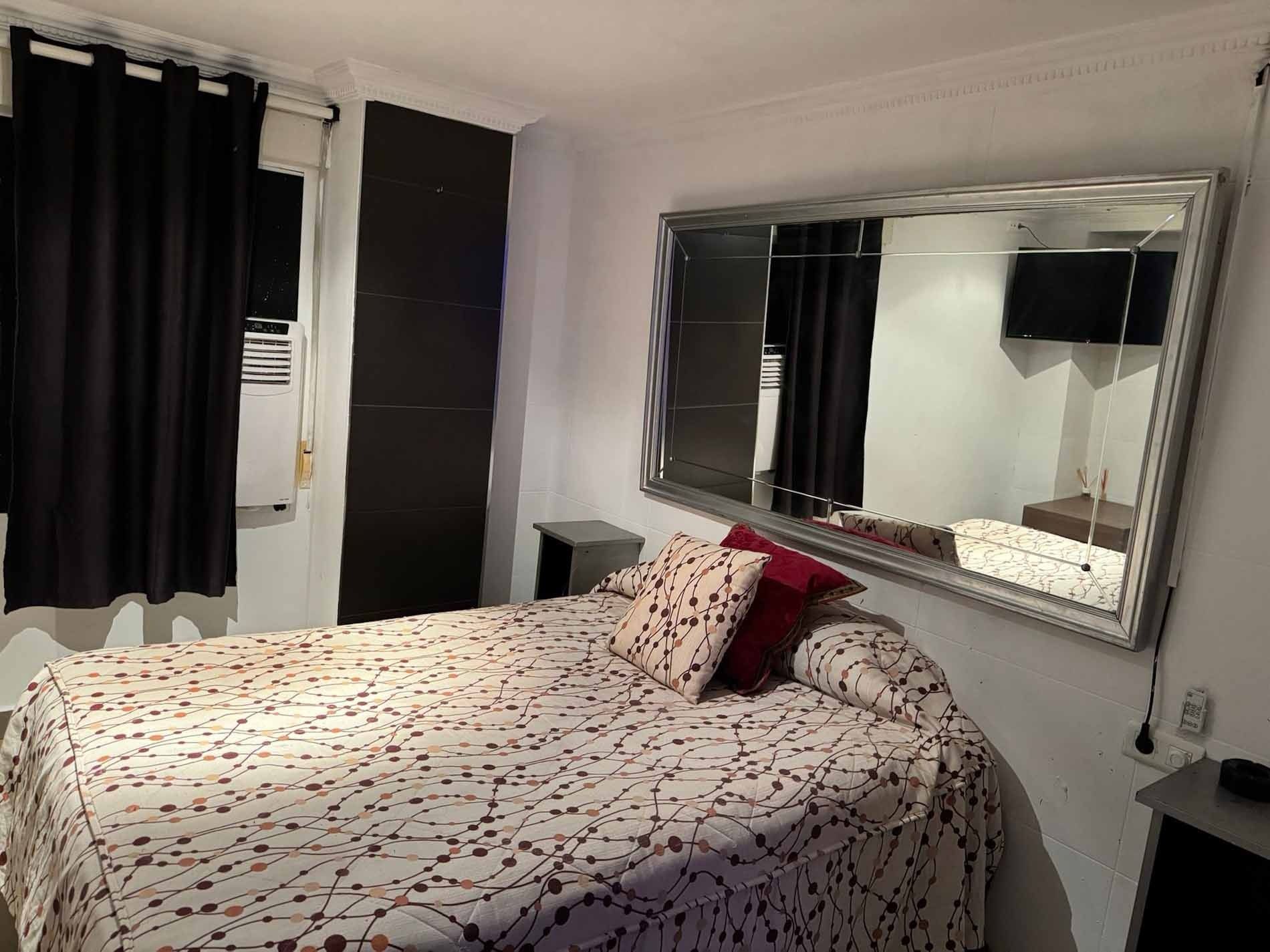 Un dormitorio con una cama y un espejo grande.