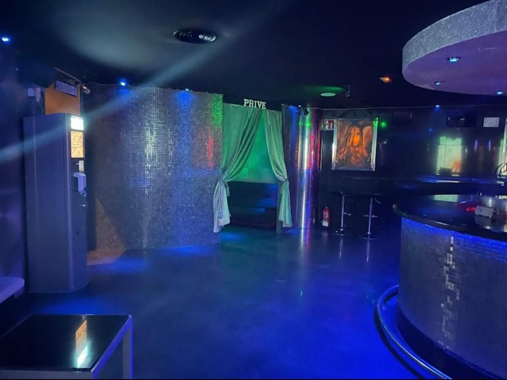 Una habitación oscura con luces azules y un bar.