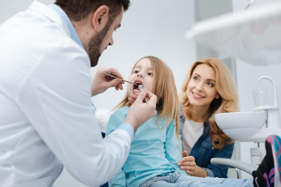 Un dentiste examine les dents d'une petite fille dans un cabinet dentaire.