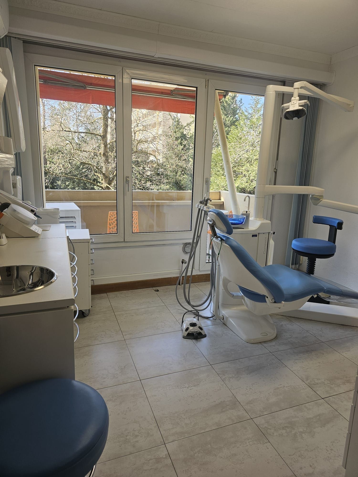 Un cabinet dentaire avec une chaise bleue et un lavabo