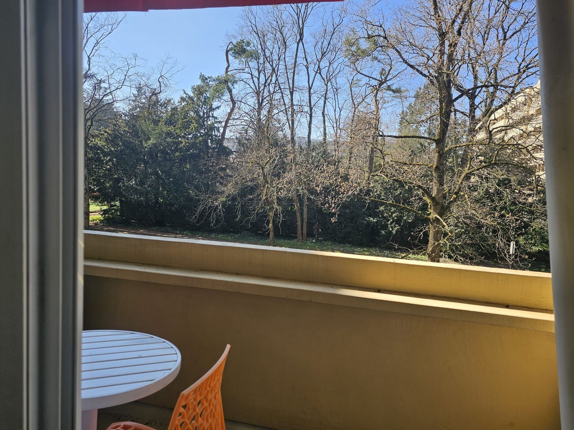 Un balcon avec une table et des chaises et une vue sur les arbres.