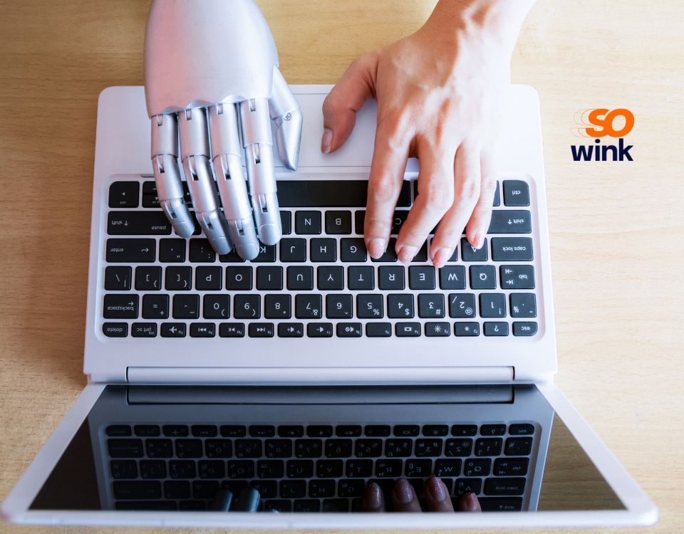 Une main humaine et une main robotique utilisant un clavier d'ordinateur portable.