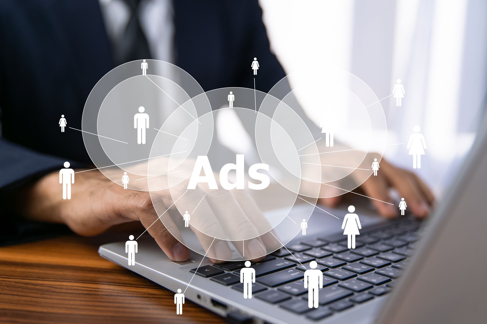 Une personne tapant sur un ordinateur portable avec une superposition numérique d'un graphique « Publicités » relié à des icônes en forme humaine.