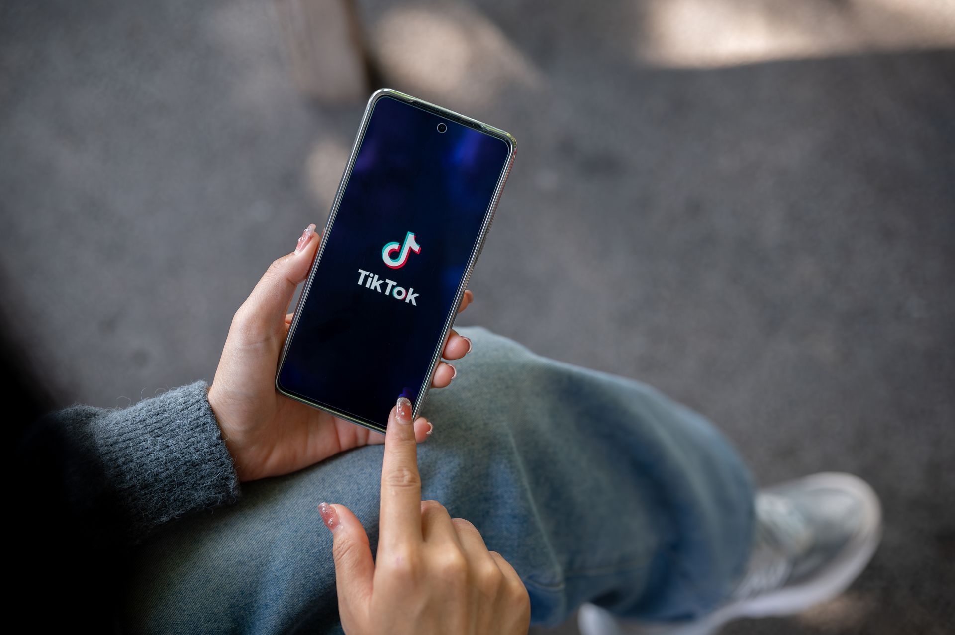 Une personne tient un smartphone affichant le logo TikTok sur son écran.