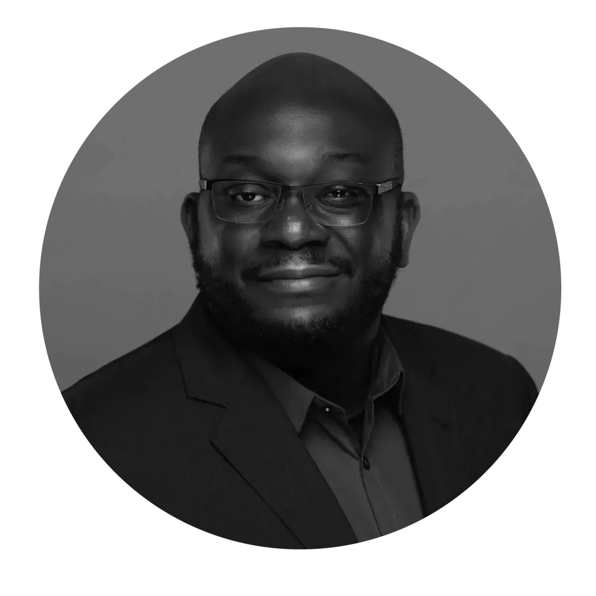 Portrait d'une personne portant des lunettes et une veste de costume, centré dans un cadre circulaire sur fond gris uni.