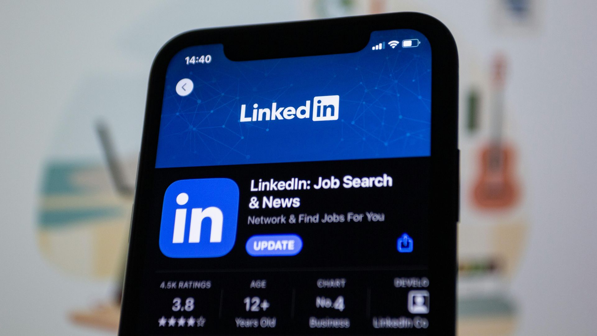 L'écran d'un smartphone affiche la page LinkedIn de l'App Store avec un bouton « Mettre à jour » visible sur un fond bleu.