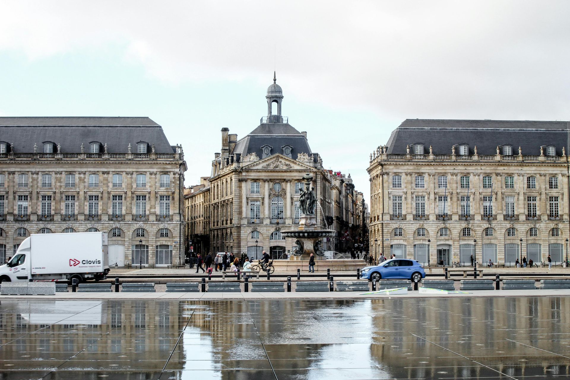 La place de la Bourse à Bordeaux, en France, avec son architecture classique se reflétant dans une place pavée et humide.