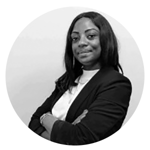 Une personne vêtue d'un blazer noir et d'un haut blanc, les bras croisés, se détache sur un fond neutre à l'intérieur d'un cadre circulaire.