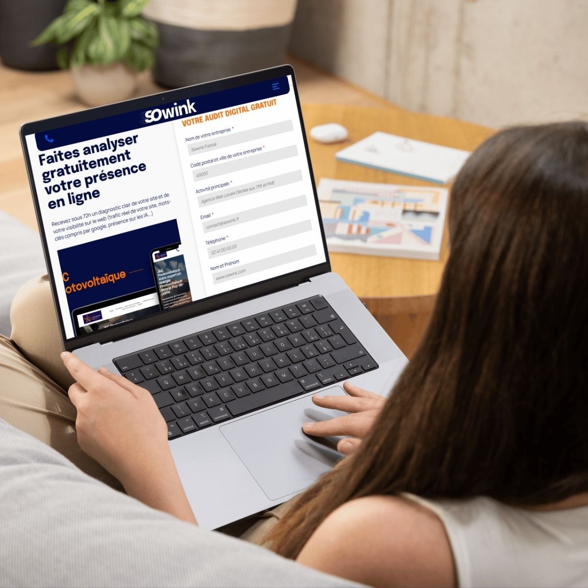 Une personne est assise sur un canapé et utilise un ordinateur portable pour consulter un formulaire en vue d'une analyse de présence en ligne.