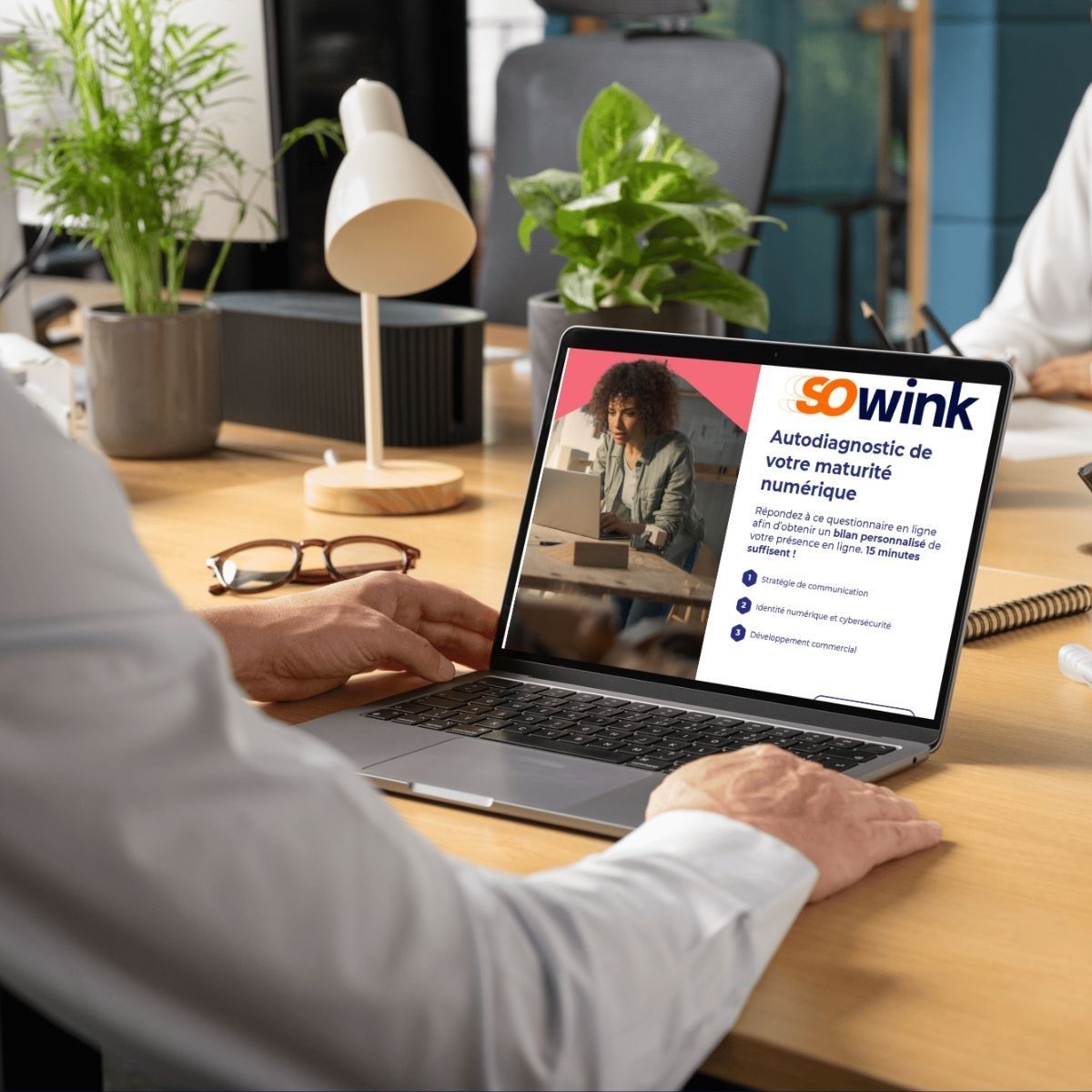 Une personne travaillant sur un ordinateur portable affichant un outil d'évaluation numérique de « sowink » dans un bureau moderne et lumineux.