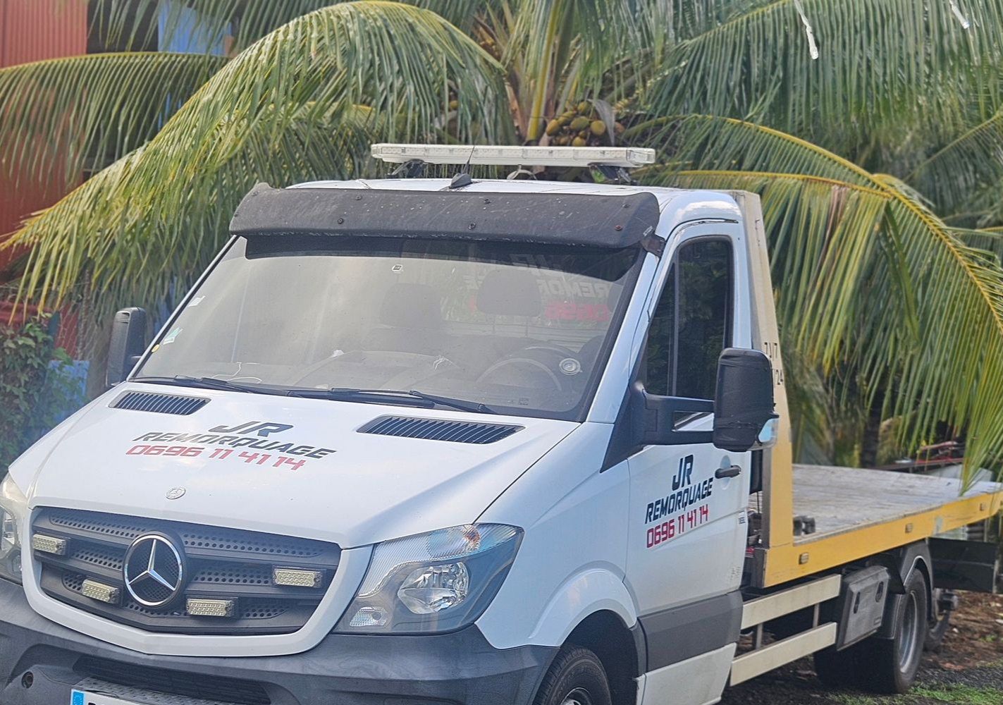 Camion de dépannage de JR REMORQUAGE blanc à plateau, stationné à l'extérieur.