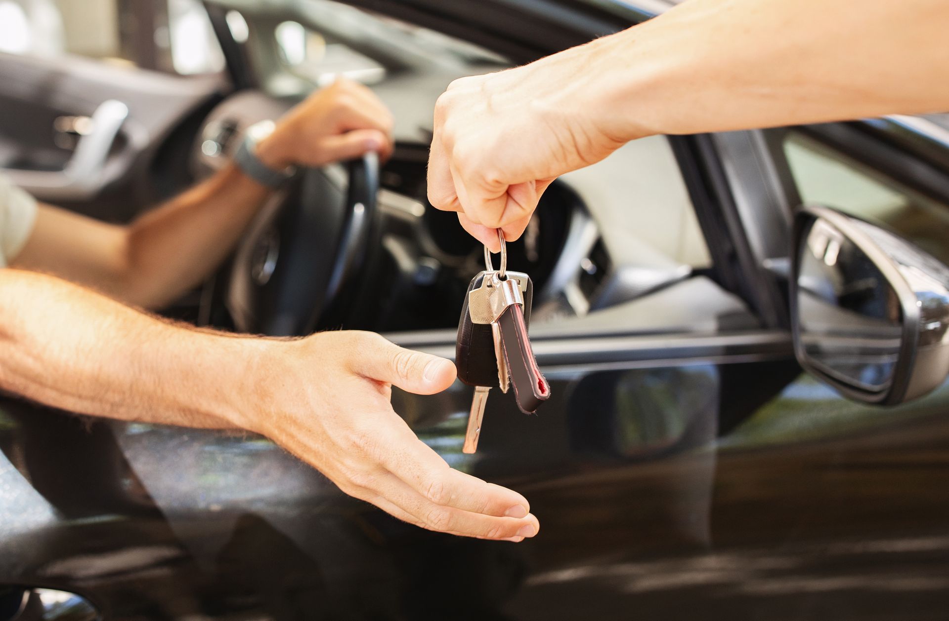 Une personne remet des clés de voiture à une autre à côté d'une voiture.