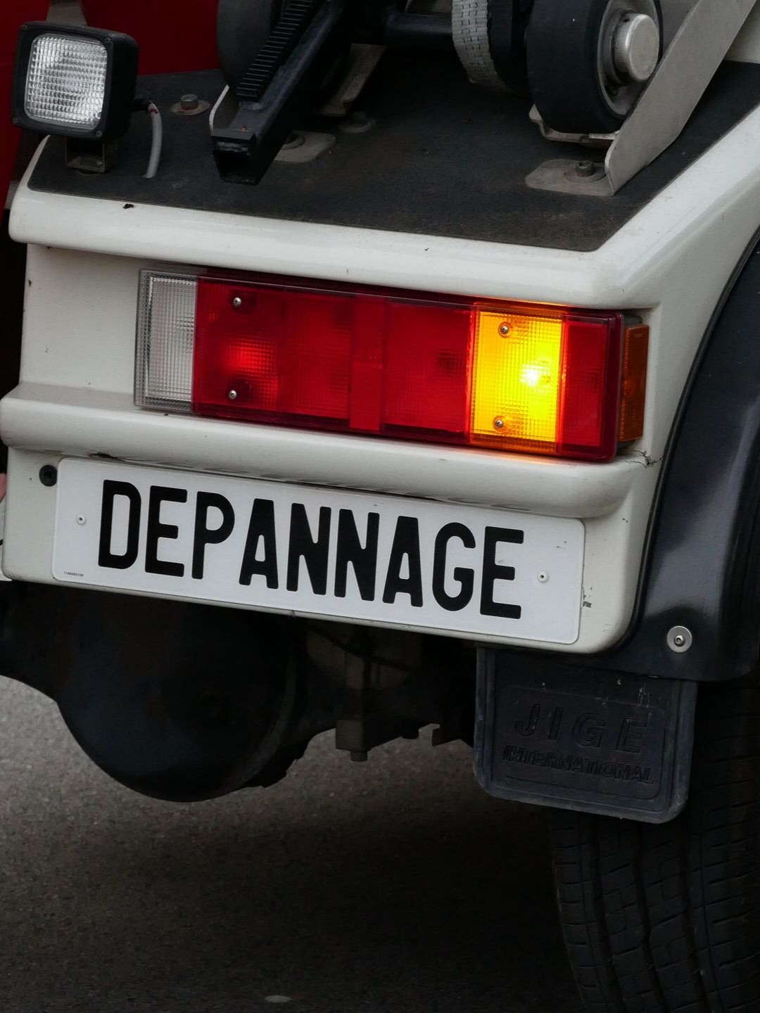 Arrière d'un camion blanc avec une plaque où il est écrit Dépannage.