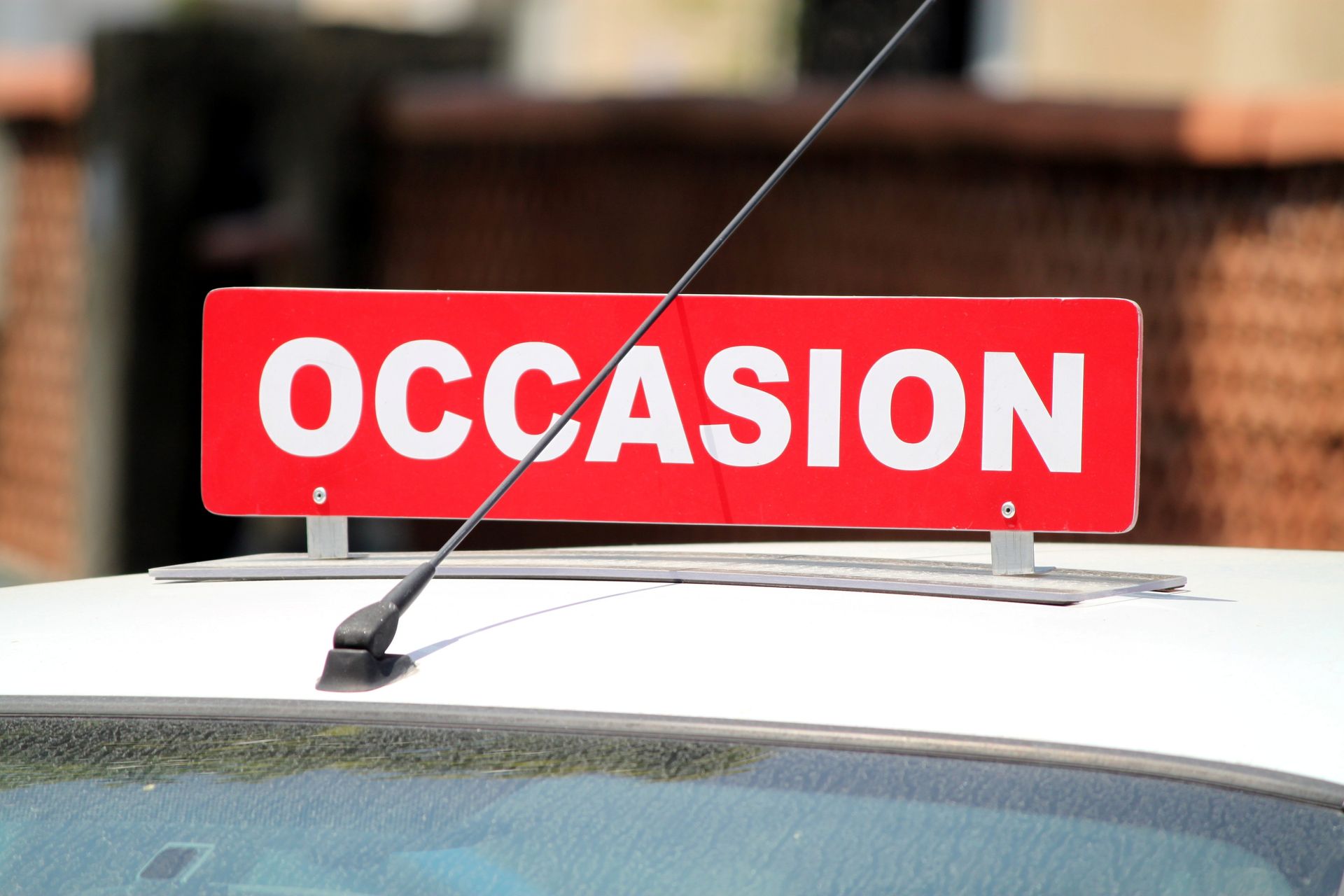 Panneau OCCASION sur le toit d'une voiture.