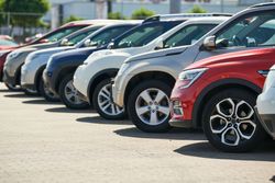Rangée de SUV et de voitures stationnés sur le parking d'une concession automobile, comprenant des véhicules.