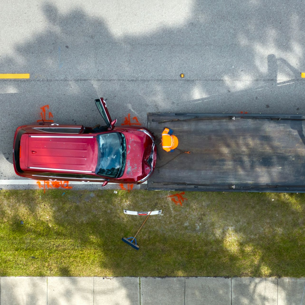 Vue aérienne d'un SUV rouge accidenté montant sur le plateau d'un camion de remorquage.