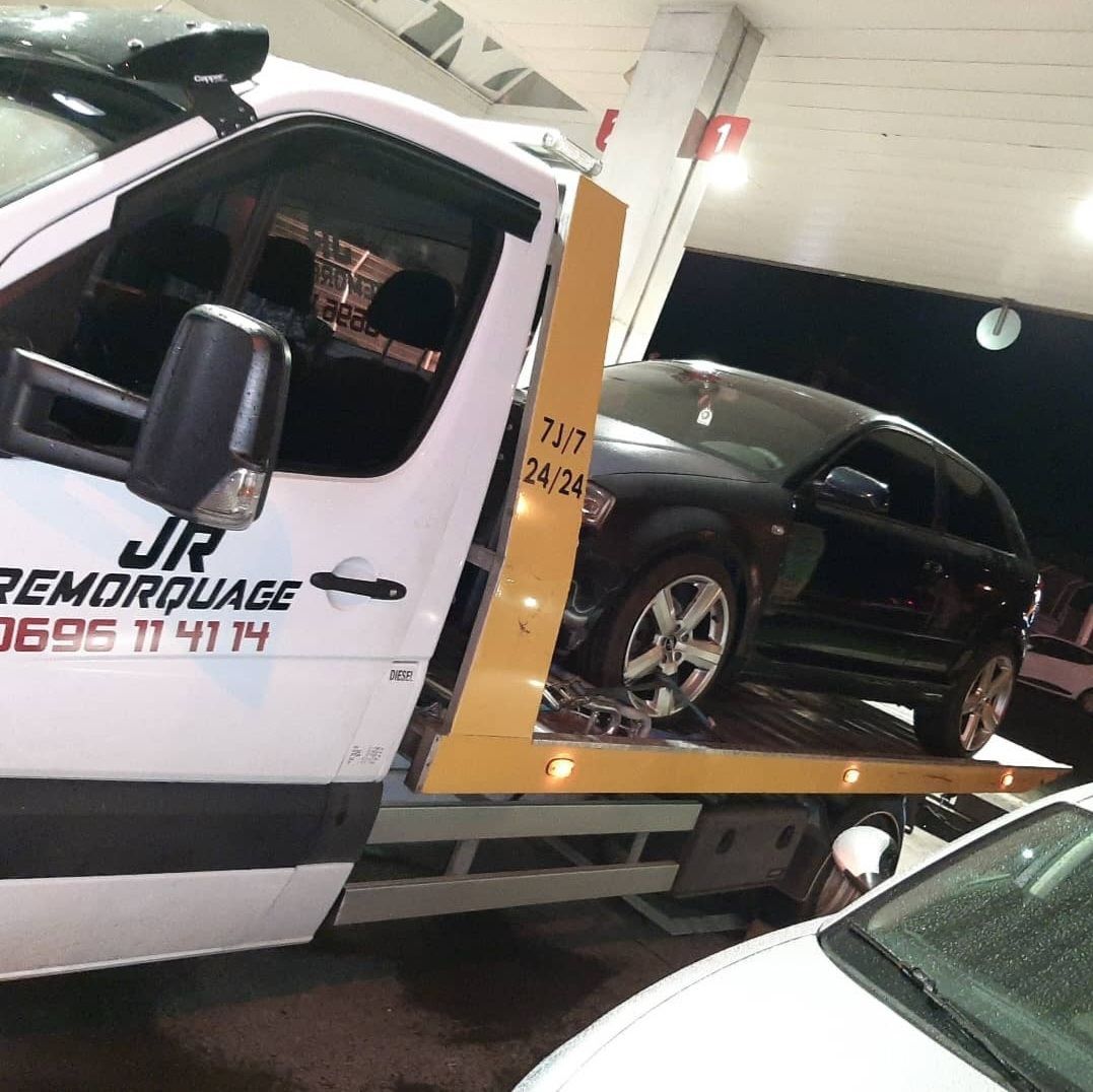 Voiture noire sur la dépanneuse de JR REMORQUAGE dans une station-service.