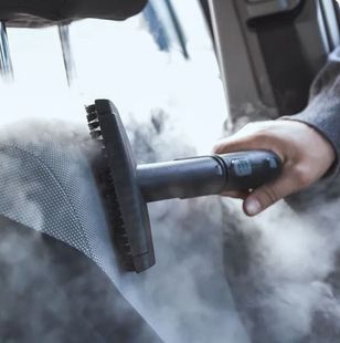 Una persona está limpiando un coche con un limpiador a vapor.