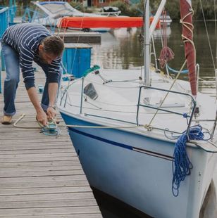 Un hombre está pintando un velero en un muelle.