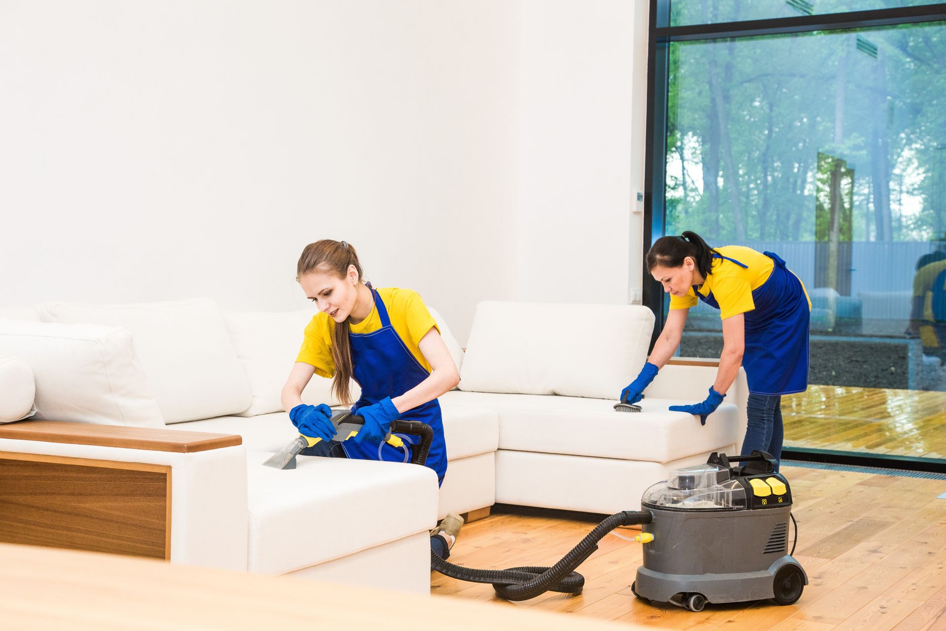 Dos mujeres están limpiando una sala de estar con una aspiradora.
