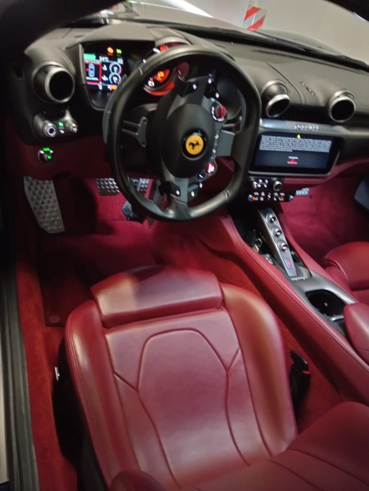 El interior de un Ferrari con asientos rojos y volante.
