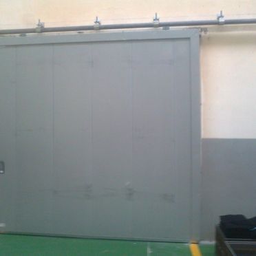 Una gran puerta corrediza gris está en una habitación con piso verde.