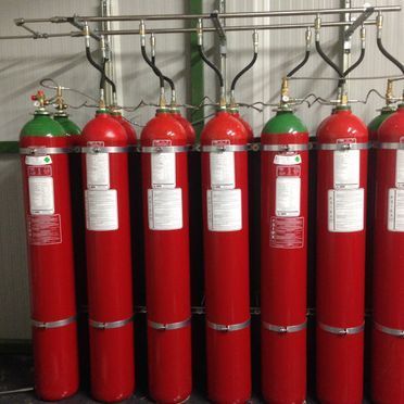 Una fila de cilindros de gas rojos están alineados en una habitación.