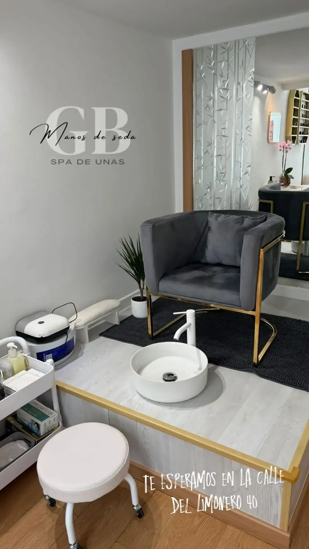 Un salón con sillón de terciopelo gris, zona de remojo para pies y el logotipo