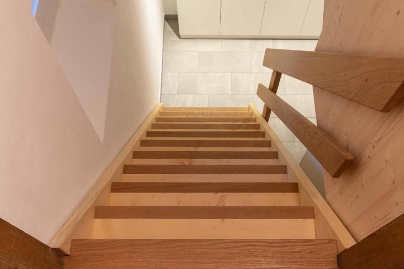 Eine Holztreppe, die in den zweiten Stock eines Hauses führt.