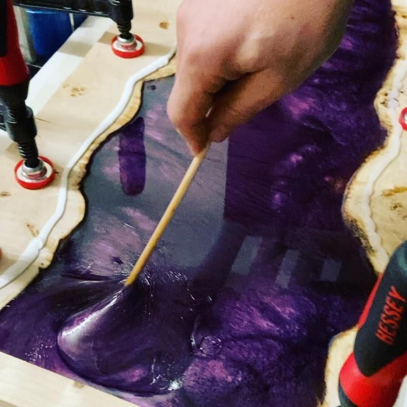 Eine Person verteilt das Giessharz mit einem Holzstab