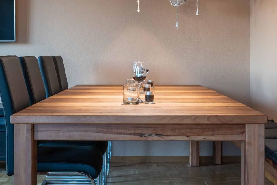 Ein Holztisch mit einem Glas Wein darauf in einem Esszimmer.