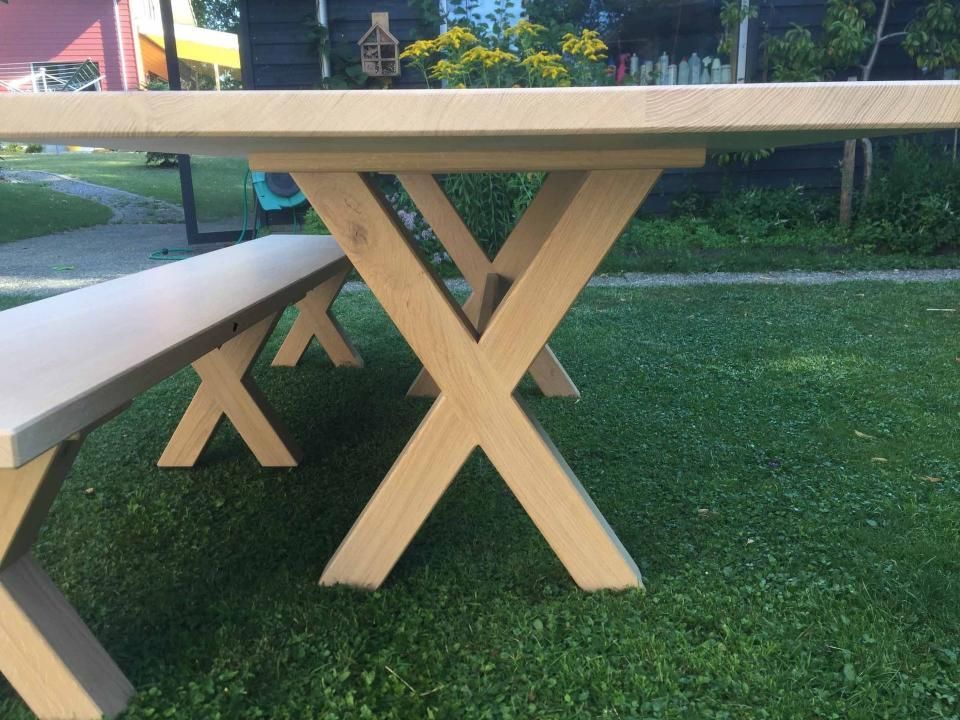 Ein hölzerner Picknicktisch mit zwei Bänken auf einer üppigen grünen Wiese.