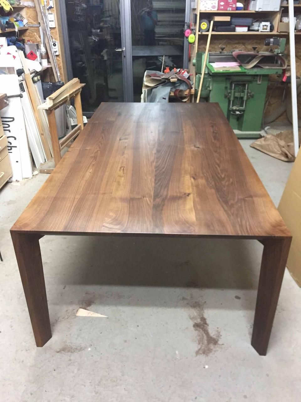 Ein Holztisch in einer Werkstatt mit einem grünen Mülleimer im Hintergrund