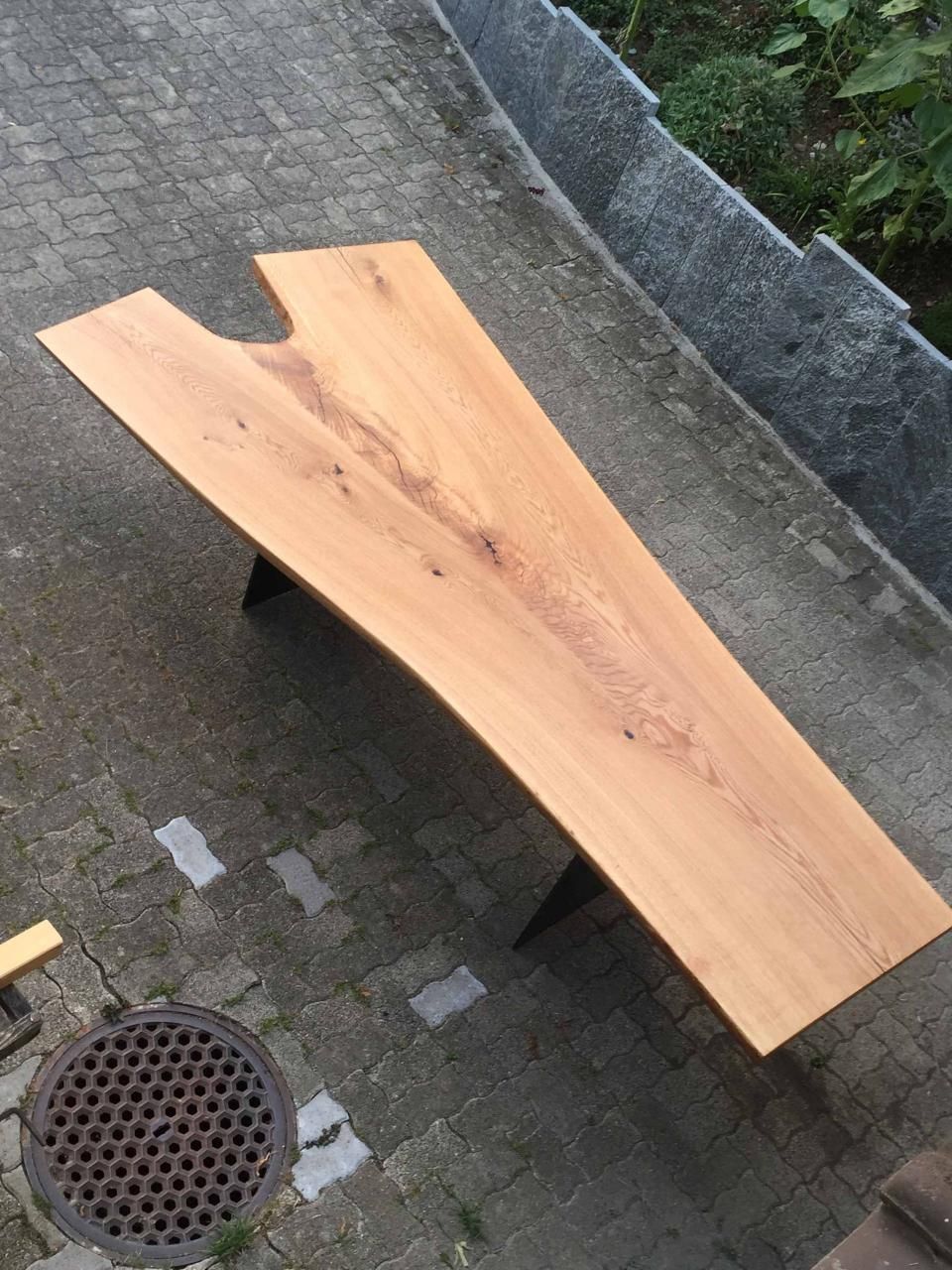 Eine Holzbank steht auf einem Gehweg 