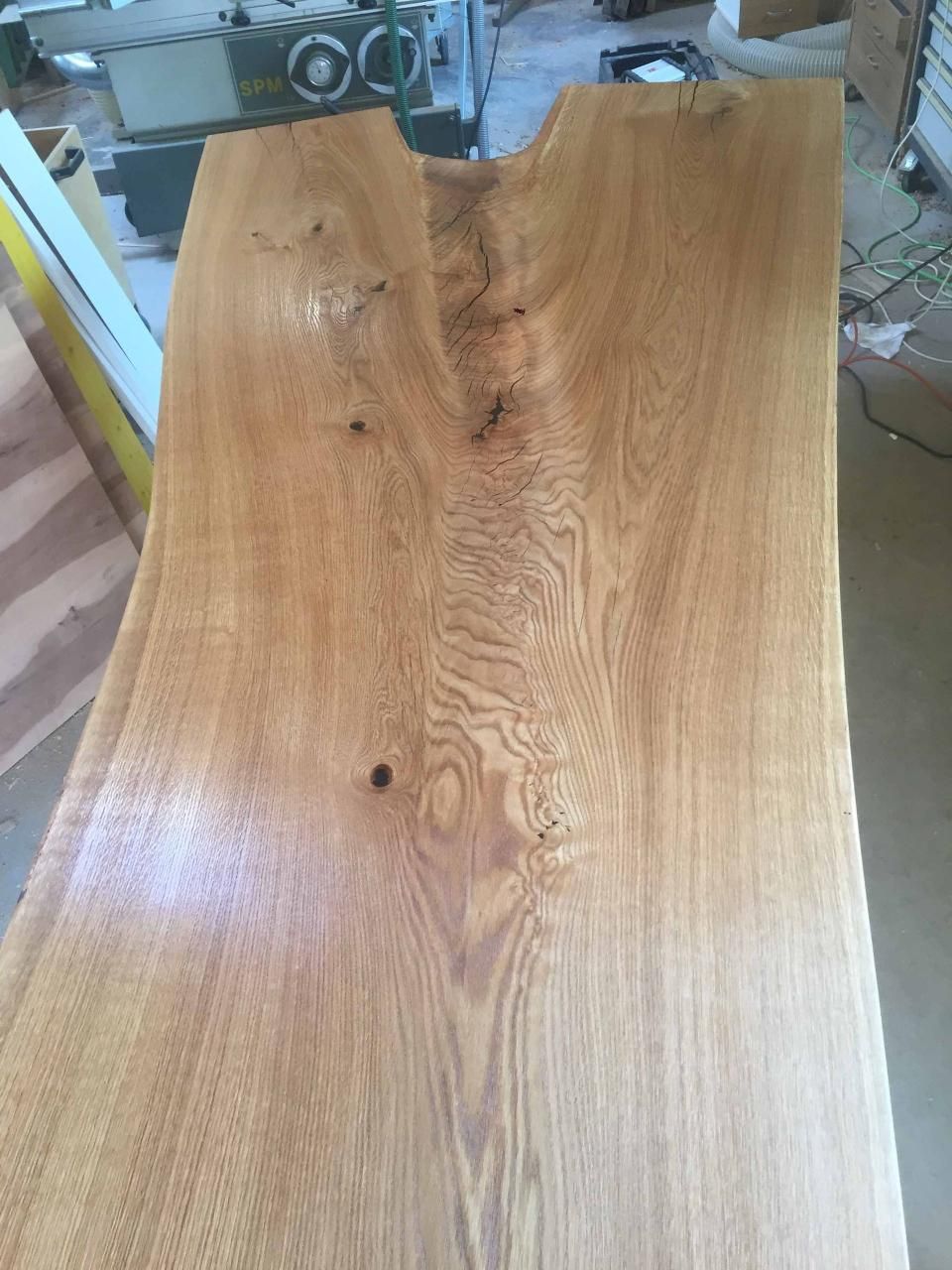 Ein großes Stück Holz liegt auf einem Tisch in einer Werkstatt.