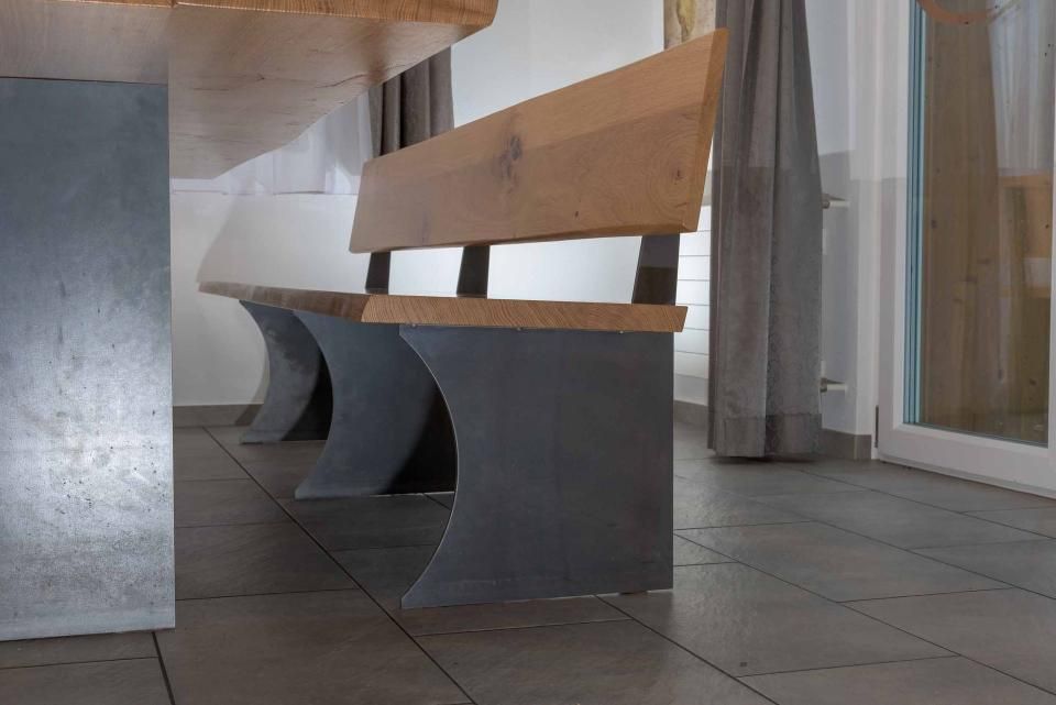 In einem Raum steht eine Holzbank neben einem Holztisch.