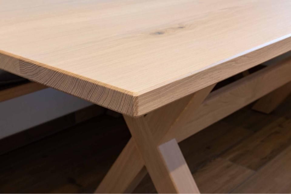 Eine Nahaufnahme eines Holztisches mit einer Holzbank darunter.